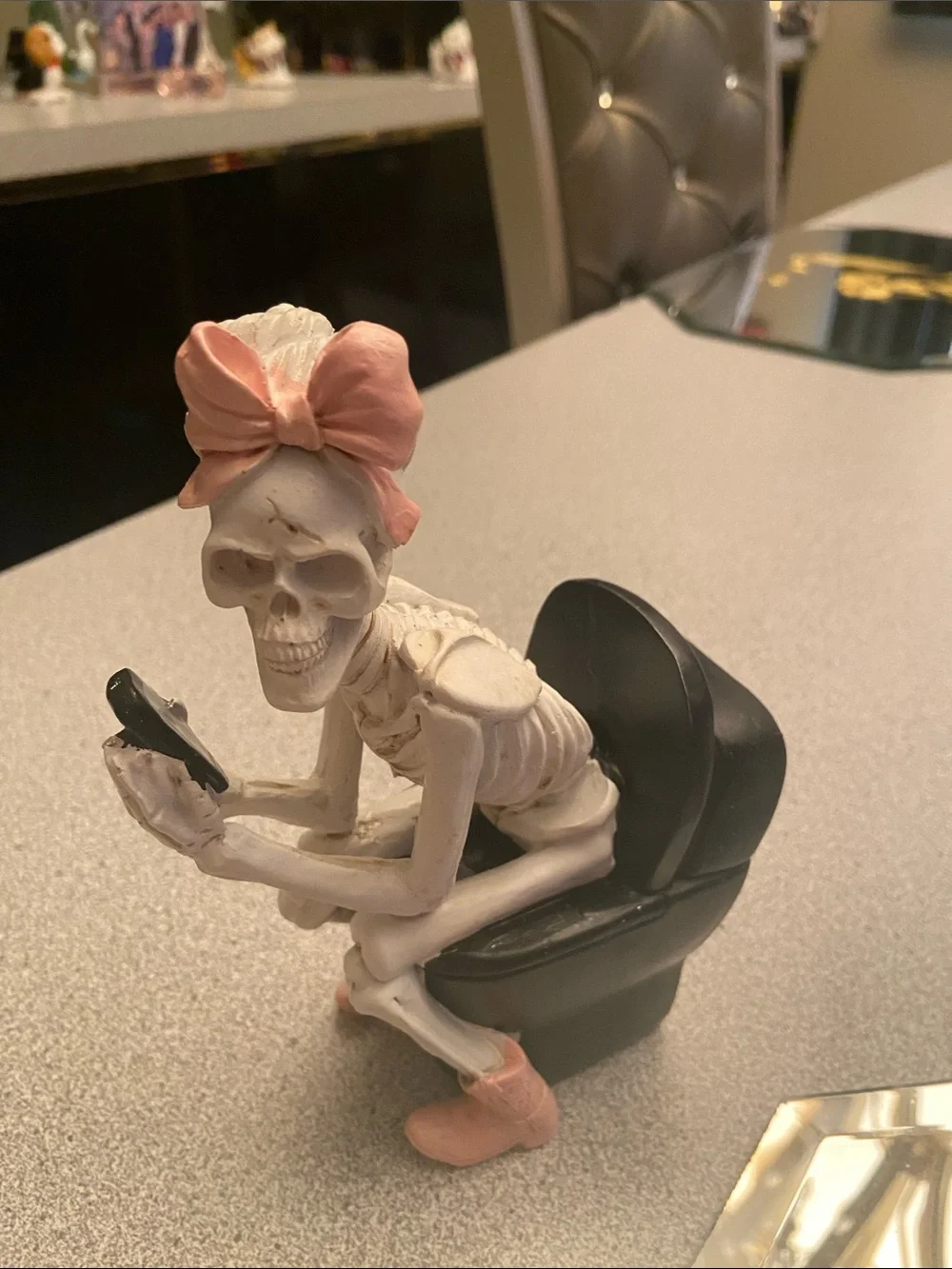 Pink-Bow Skeleton Figurine Sitting on Black toilet chair